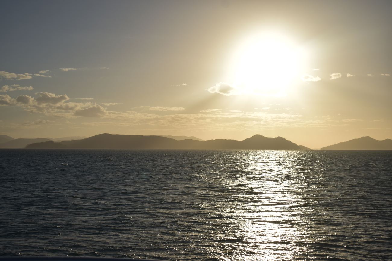 The sun dropping low over layered islands, gold on the water