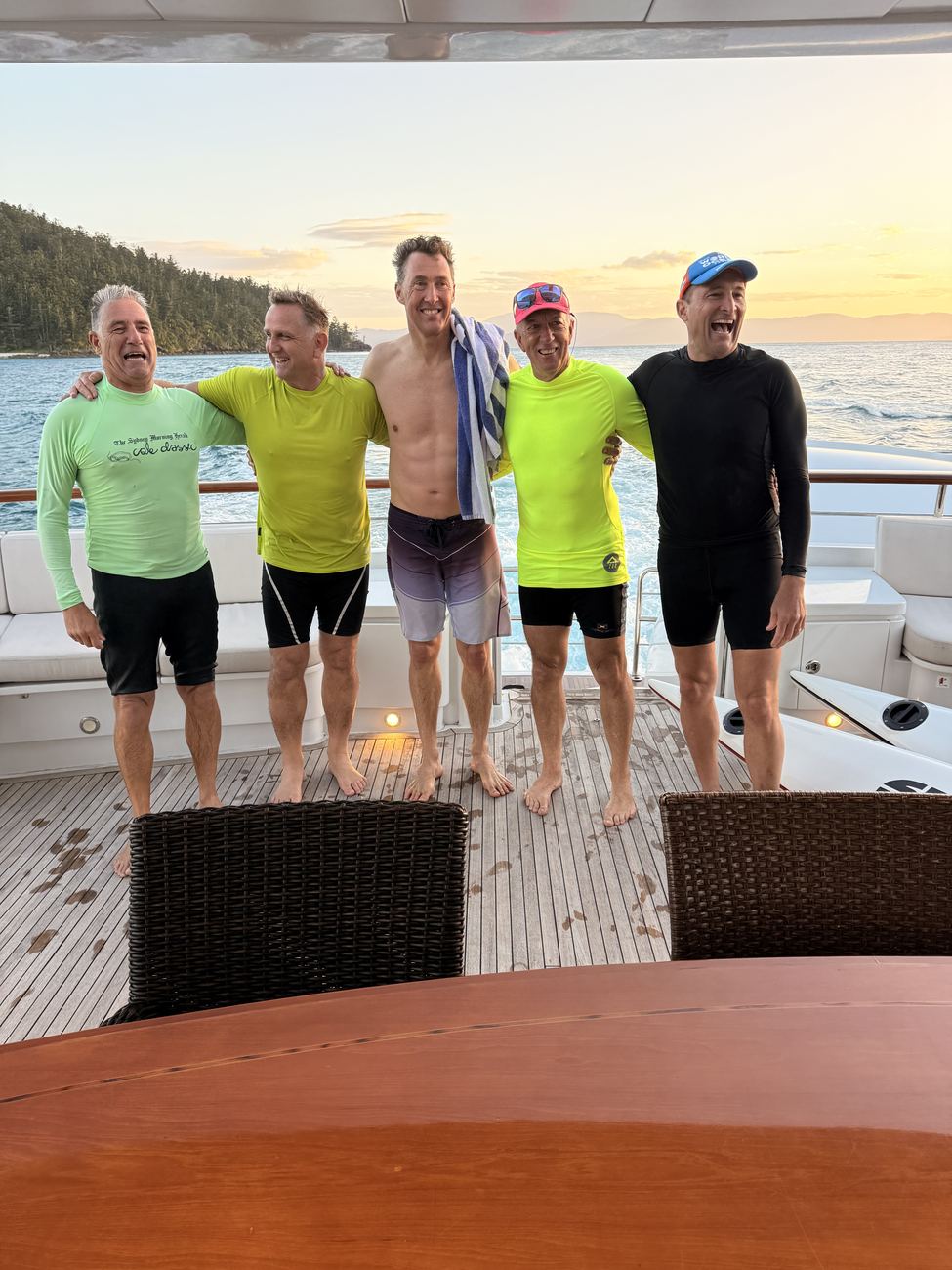 The five paddlers arm in arm on the aft deck at sunset