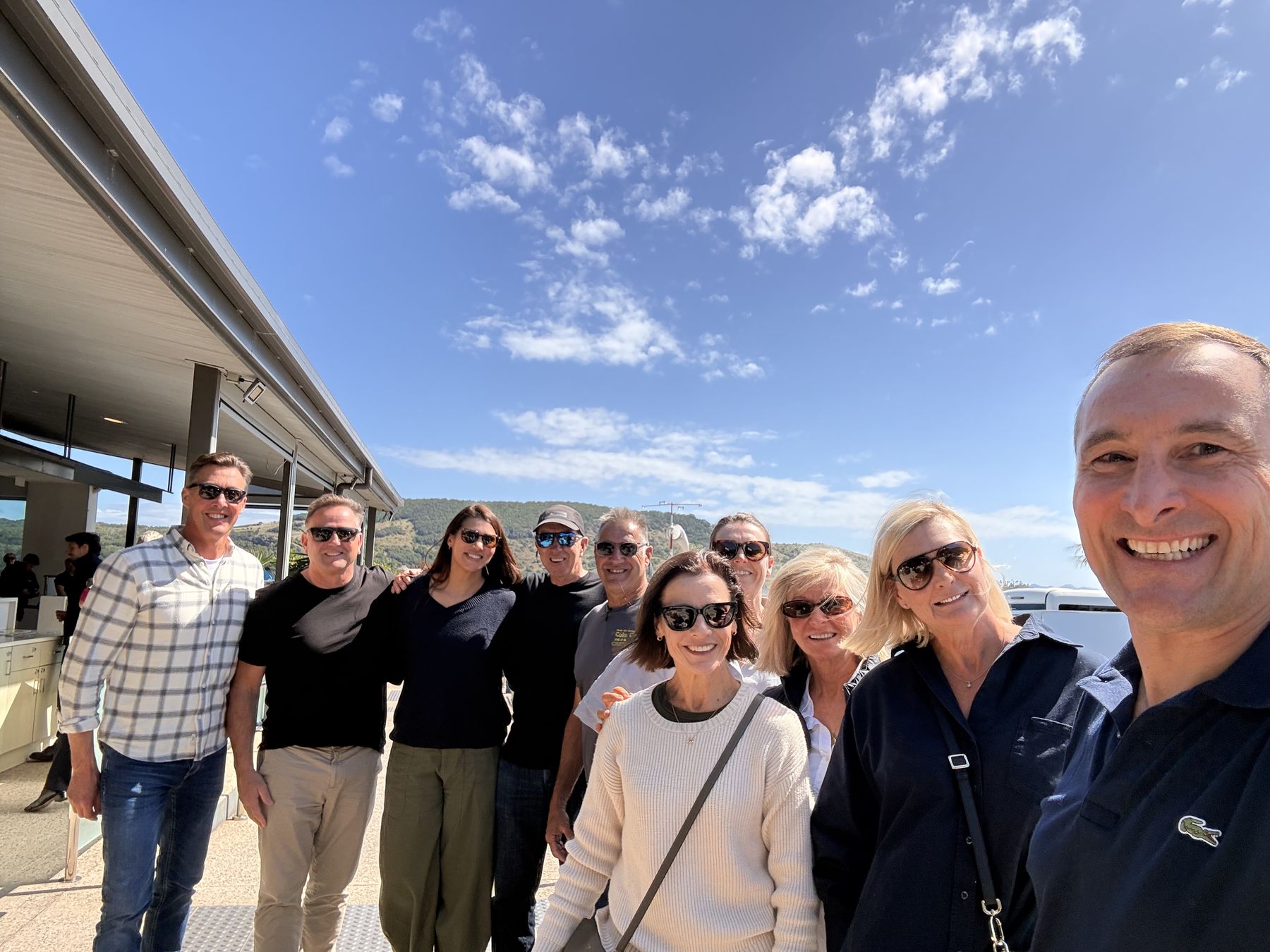 The company arrives at Hamilton Island, all smiles under a blue winter sky