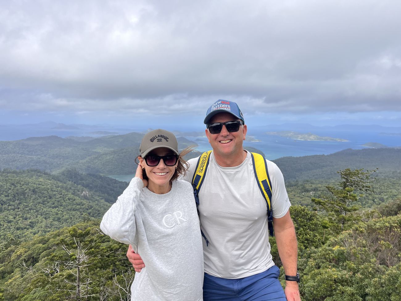 Two hikers at the summit with islands behind