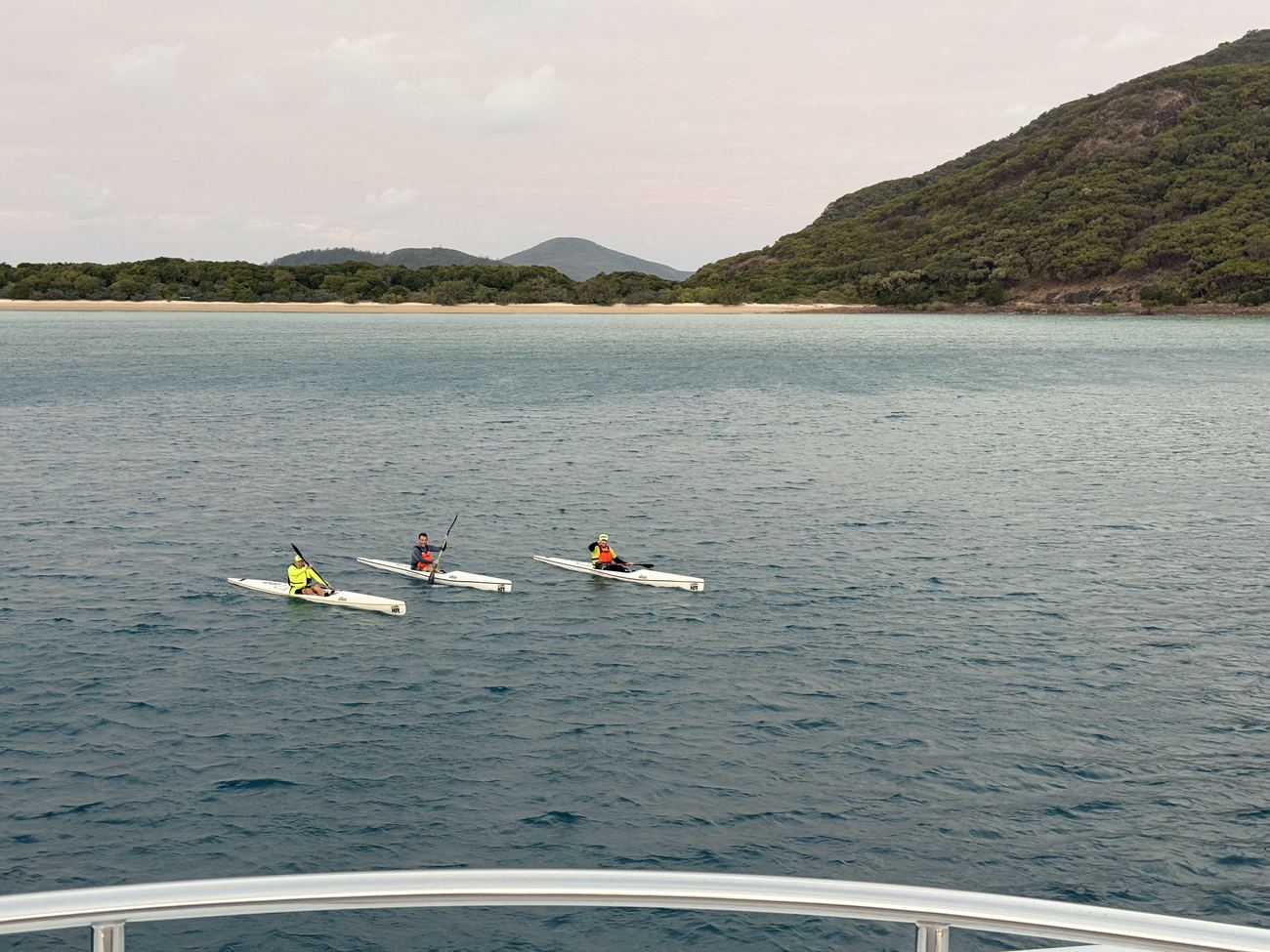 Three surf skis on glassy evening water below the bow