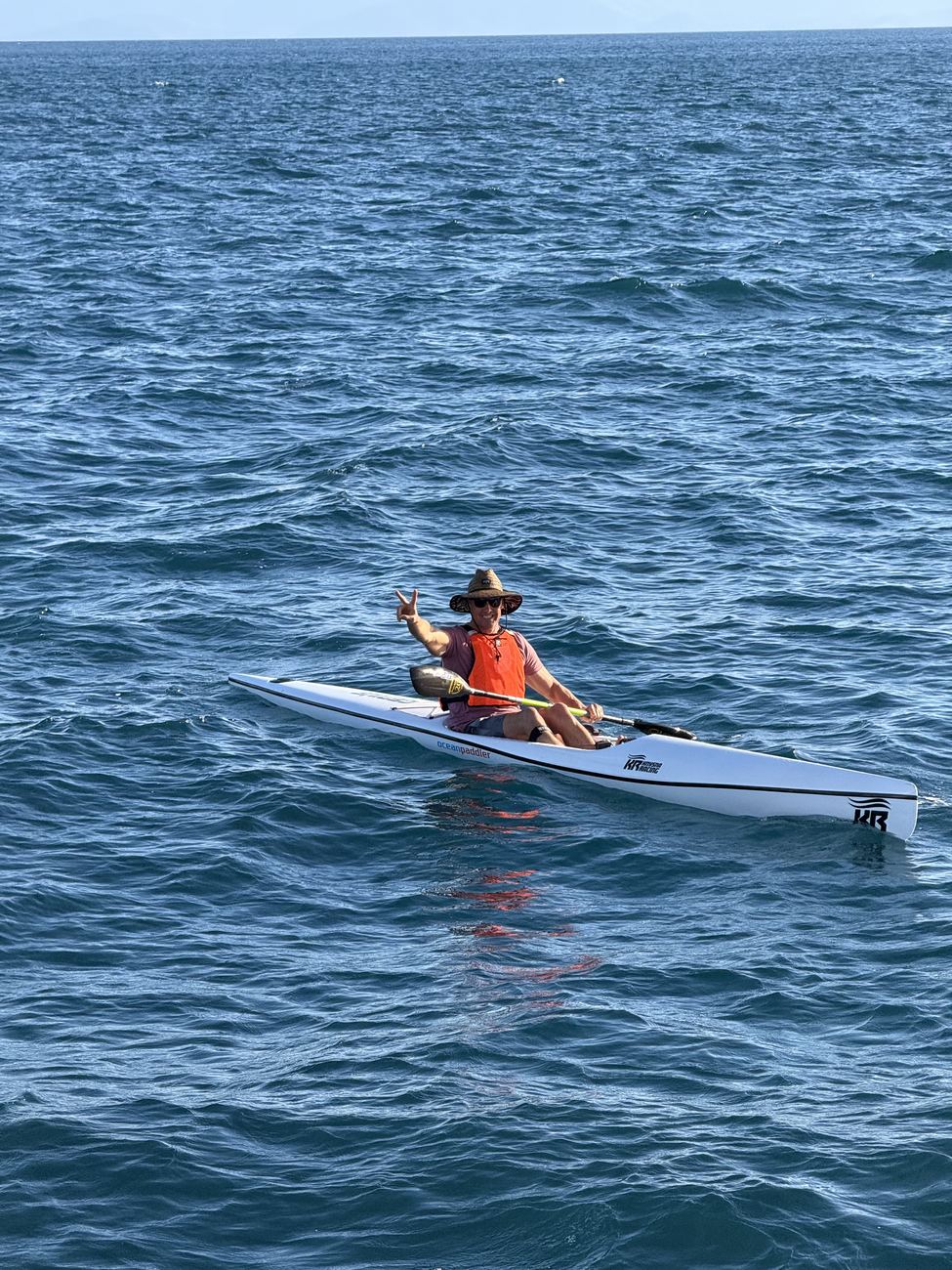 A paddler tipping their hat from the ski in golden light