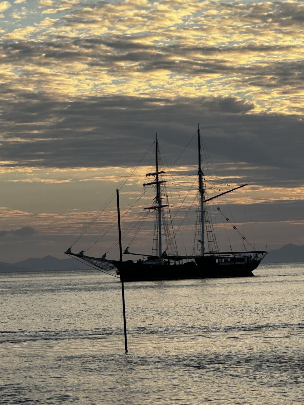 A tall ship silhouetted at anchor at dusk