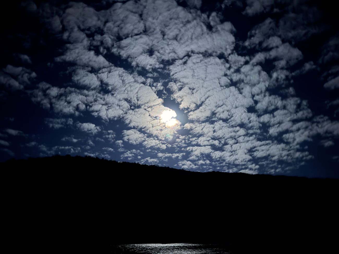 The full moon burning through a field of mackerel clouds