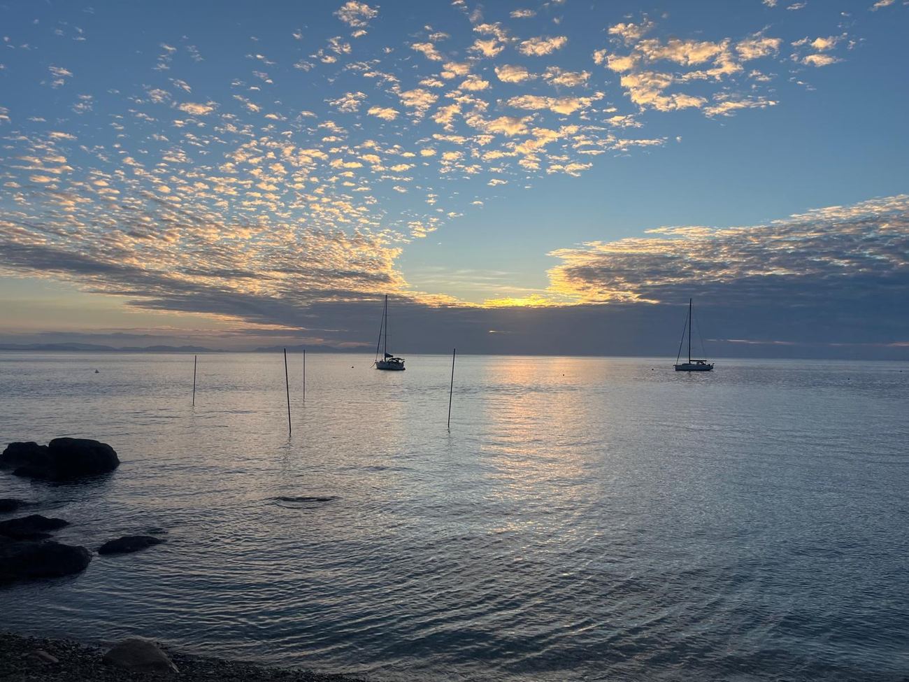 The sun setting over open water at Castle Rock, boats at anchor
