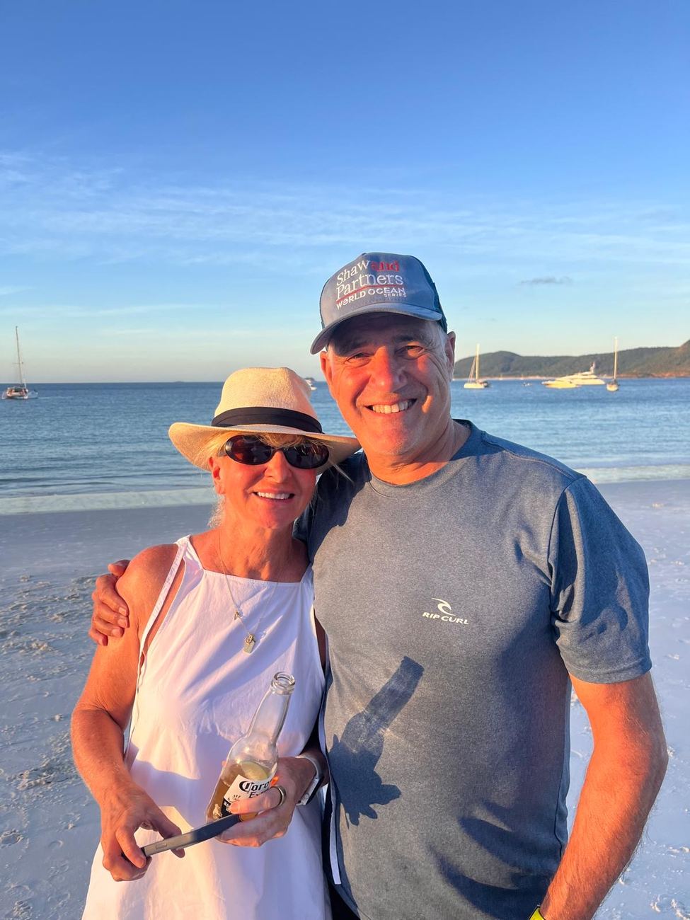 Couple in whites and hats on the beach at dusk
